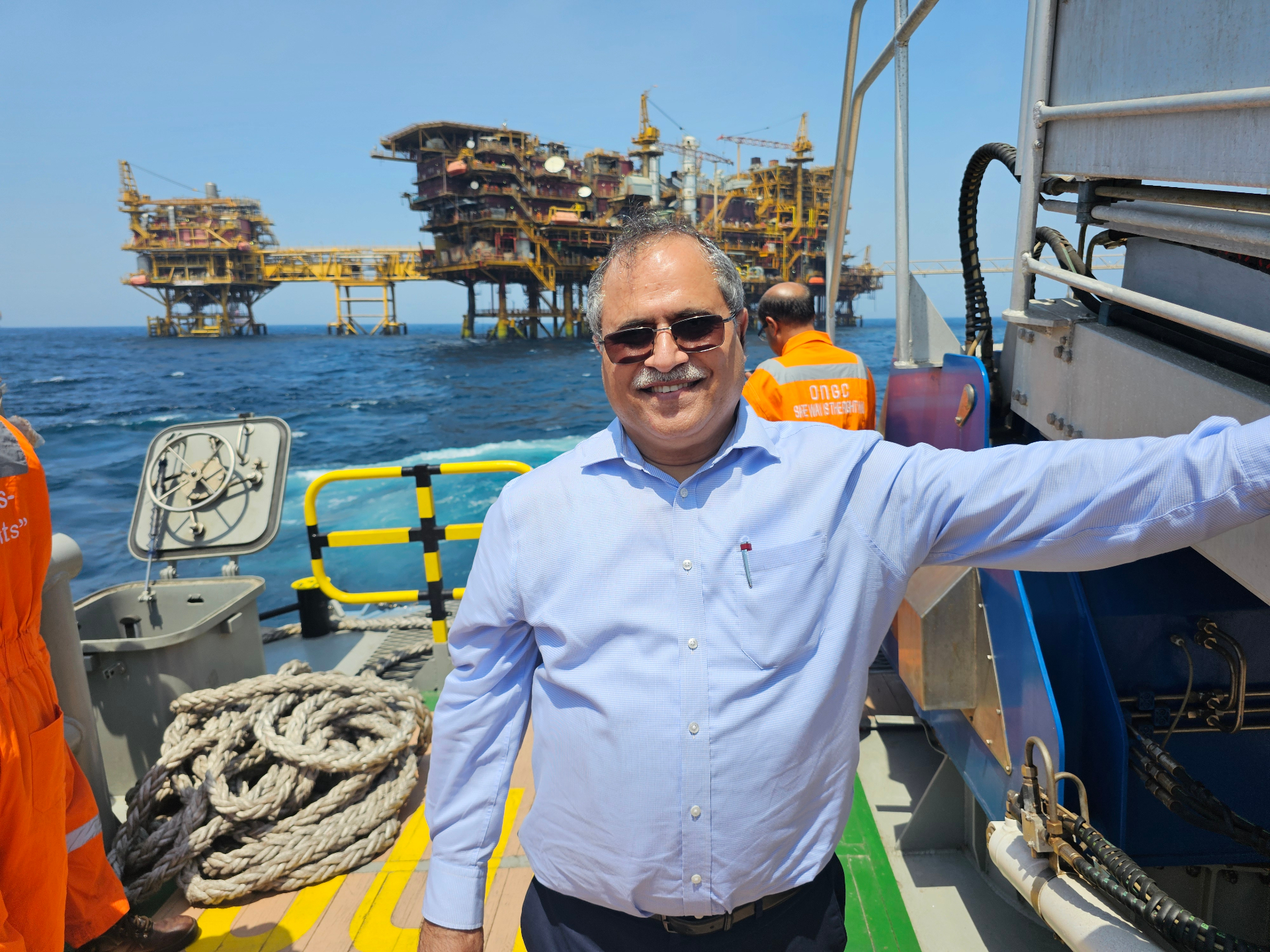 Adarsh Kumar Malpotra aboard a vessel with an offshore oil platform in the background